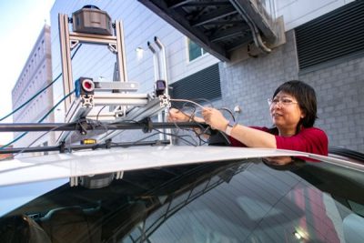 researcher works with equipment on top of car