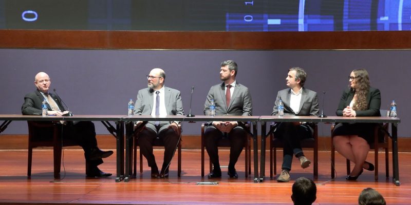 Five people sitting at a table on a stage