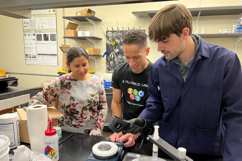 Three people work on a project in a lab