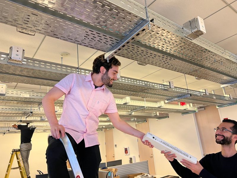 CCI 5G Testbed and AI Assurance Researcher Joao Santos taking materials from xG Testbed Intern Abdellah El Baamrani