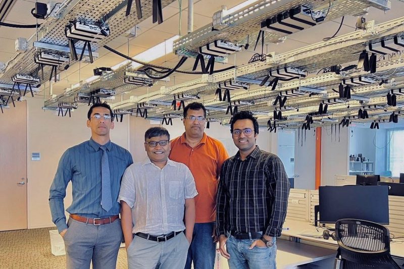 Four researchers standing in front of testbed