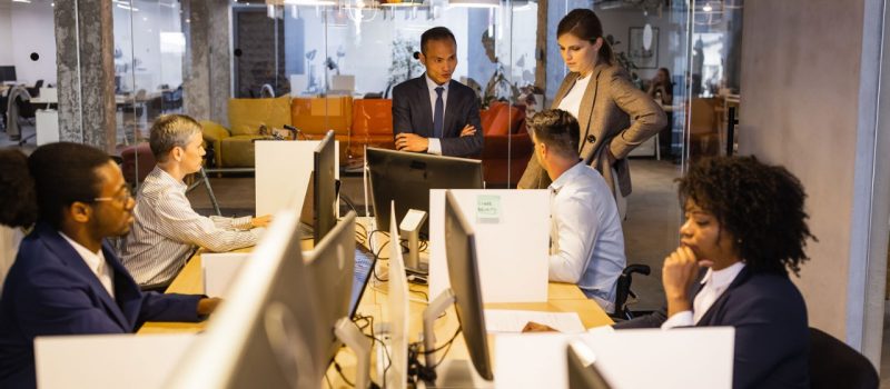 Staffers sit at communal desks working  on computers
