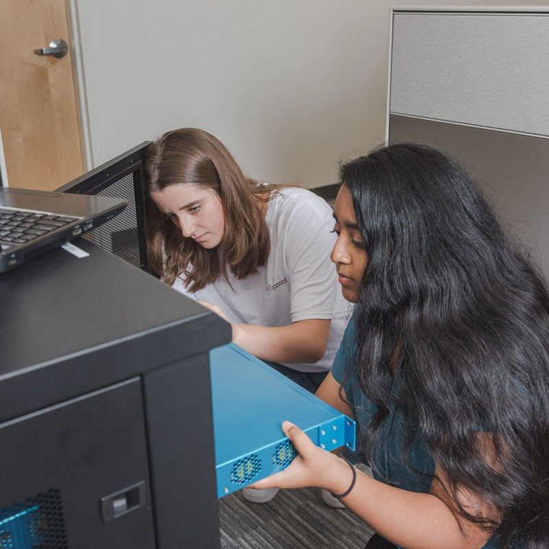 Two young women work on computer server