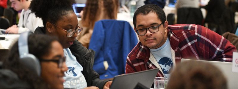 Students work on capture the flag Students around table with laptops