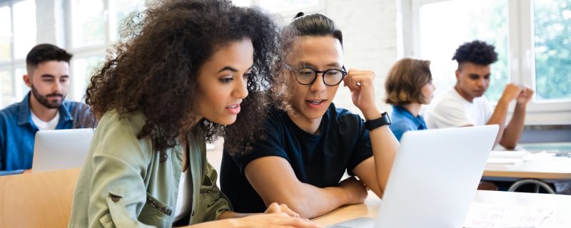 Software engineers collaborating on a project, analyzing code on laptop