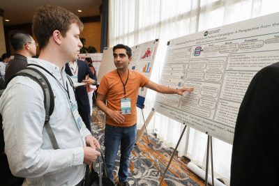 Student discusses poster with others at 2023 CCI Symposium
