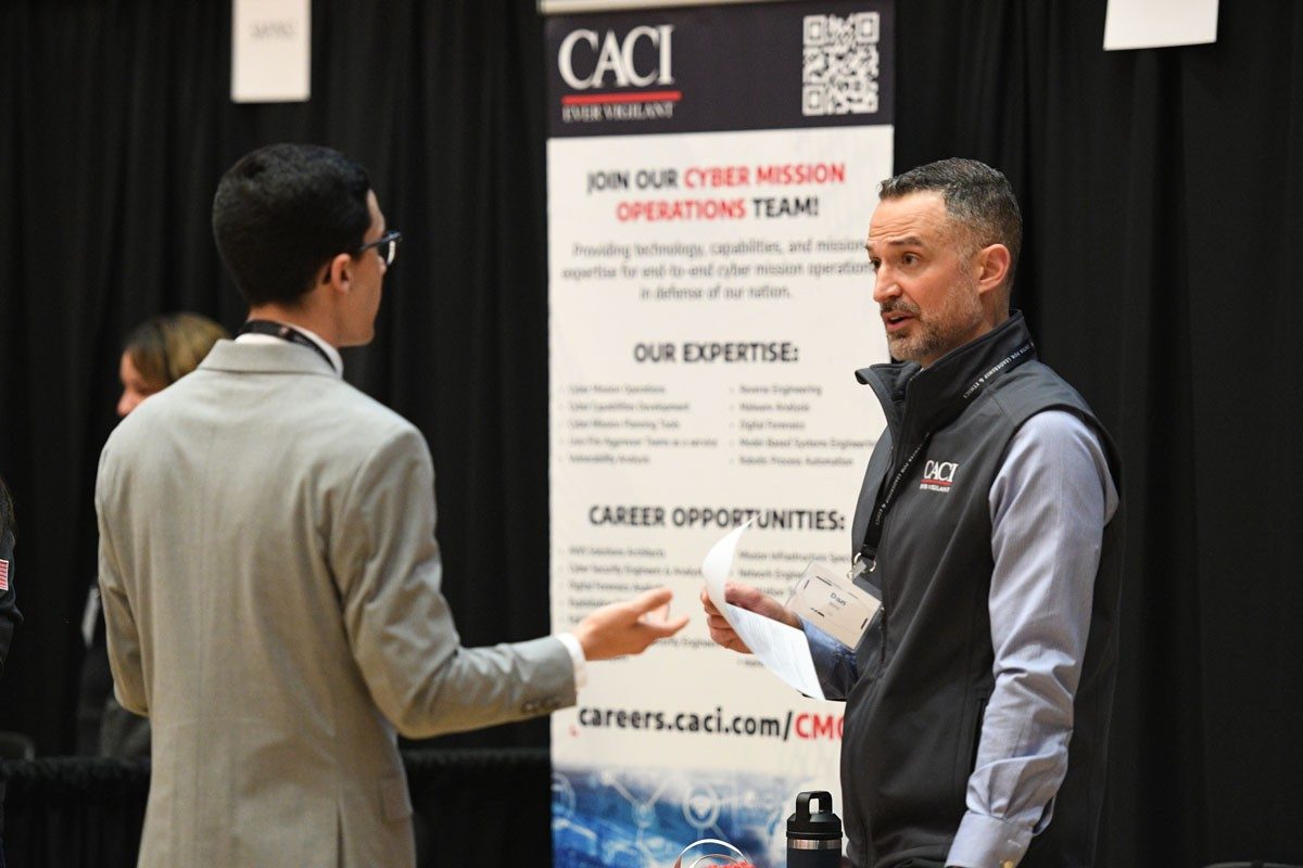 Student speaks with representative from CACI at Cyber Fusion 2024