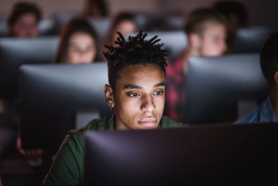 Students in darkened room work on computers