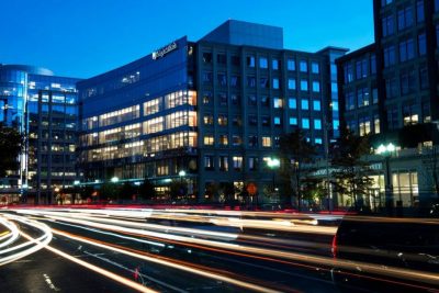 Glass building with cars passing at night