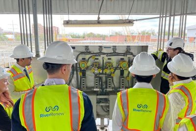 People in hard hats and safety vests in front of water treatment equipment