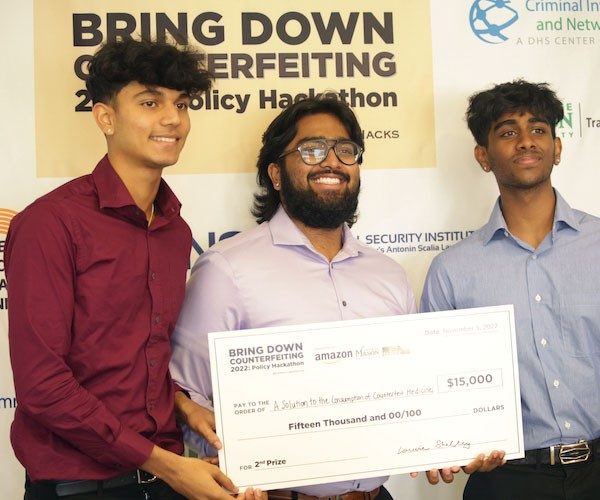 Three students hold giant check for $15,000