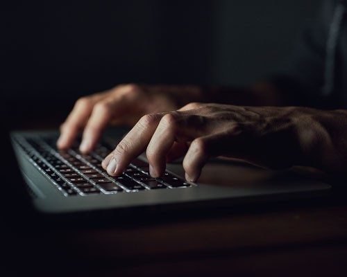 Hands typing on laptop keyboard