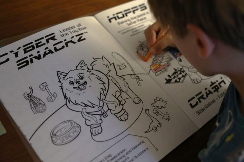 girl uses crayons to color in cyber book