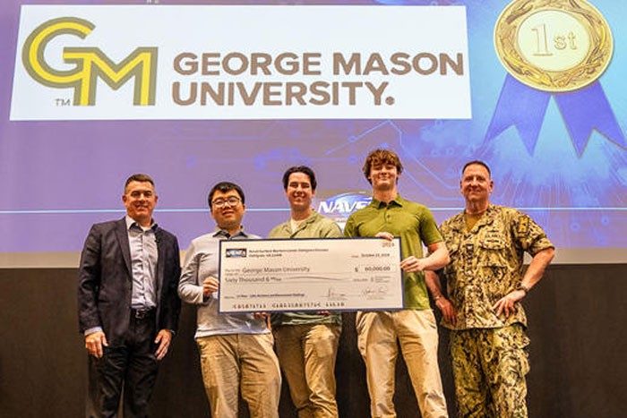 Group holds big check in front of George Mason sign