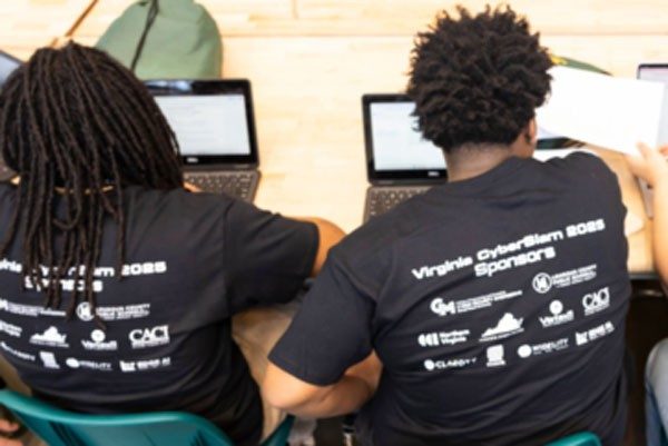 Students in Cyberslam shirts work on laptops