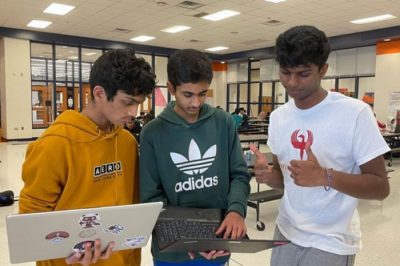 Three students look at laptop