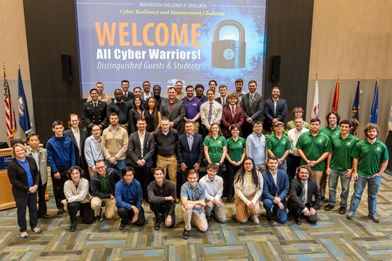 Large group of people in front of screen that says Welcome All Cyber Warriors