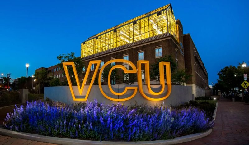 VCU sign lit up at night in front of building