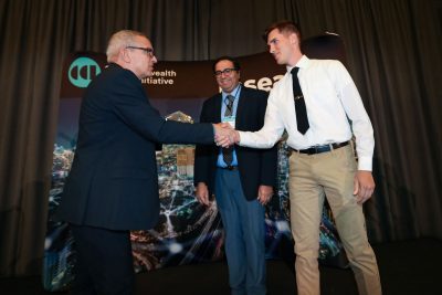 Luiz DaSilva  executive director commonwealth cyber initiative, presents award to VMI team on stage at CCI Symposium