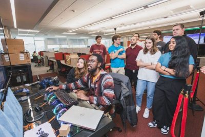 crowd of students watch other students work on computers