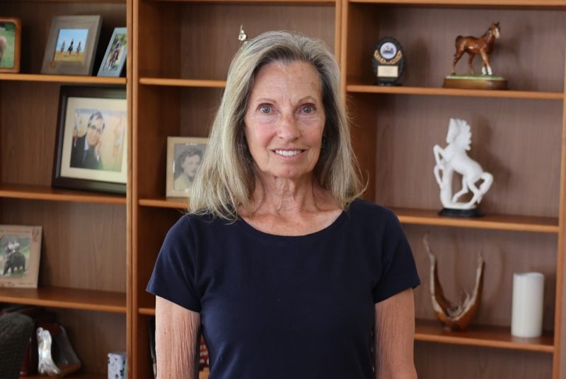 A person stands in front of a bookcase.