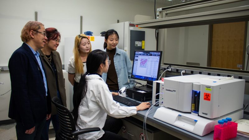 Five researchers looking at results on a computer.